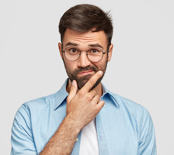 Ein nachdenklicher Mann mit Brille, der mit dem Finger an seinem Gesicht spielt.